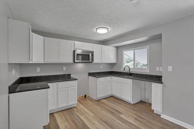 2103 Rochelle Pl, Columbus, OH 43232 - kitchen featuring stainless steel microwave, light wood-type flooring, white cabinets, a textured ceiling, and dark stone counters