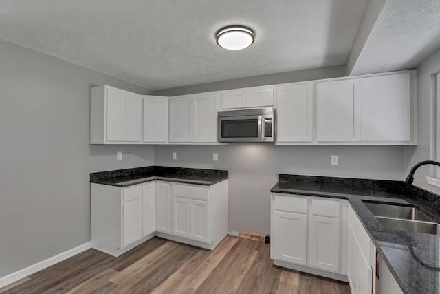 2103 Rochelle Pl, Columbus, OH 43232 - kitchen with stainless steel microwave, dark stone counters, wood finished floors, a textured ceiling, and white cabinets
