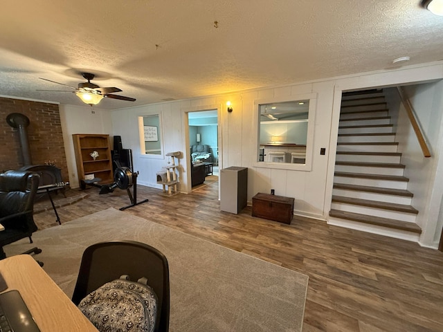 1819 Walnut Rd, Heath, OH 43056 - living room featuring a textured ceiling, wood finished floors, a wood stove, ceiling fan, and stairway