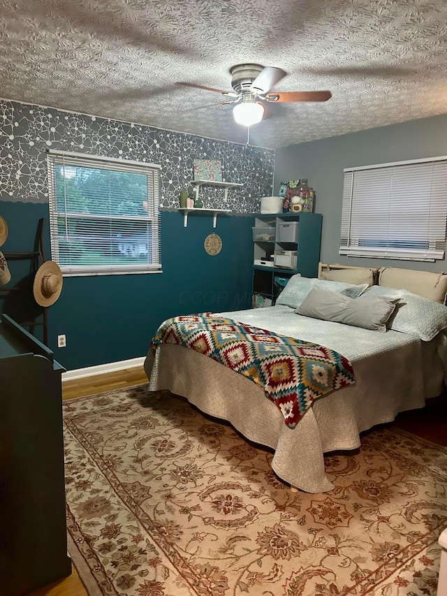 6869 Cedar Brook Pl, New Albany, OH 43054 - bedroom featuring wood finished floors, wallpapered walls, ceiling fan, and a textured ceiling
