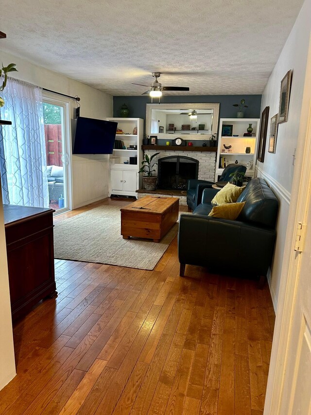 6869 Cedar Brook Pl, New Albany, OH 43054 - living area featuring a textured ceiling, wood-type flooring, a ceiling fan, and a fireplace