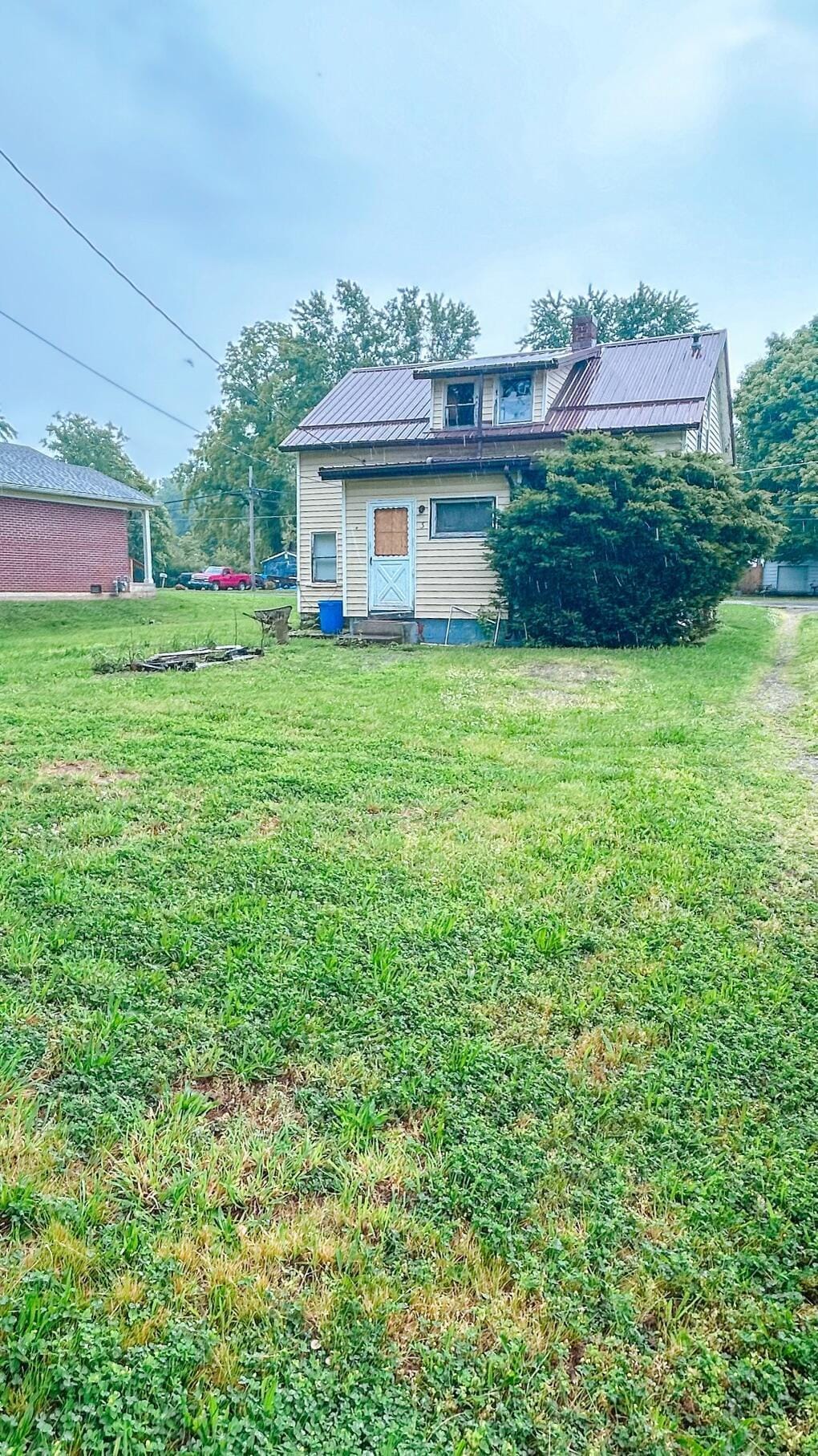 409 Lawrence St, Bellefontaine, OH 43311 - back of house featuring a lawn, a metal roof, and a chimney