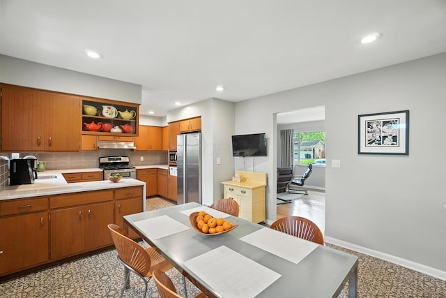 5445 Rockwood Rd, Columbus, OH 43229 - kitchen featuring stainless steel appliances, open shelves, under cabinet range hood, light countertops, and backsplash