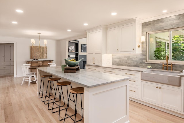 2841 Doncaster Rd, Upper Arlington, OH 43221 - kitchen featuring a kitchen island, white cabinetry, light stone counters, light wood-type flooring, and a breakfast bar