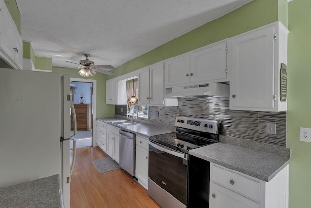 6605 Lancaster Rd SE, Hebron, OH 43025 - kitchen with appliances with stainless steel finishes, under cabinet range hood, tasteful backsplash, light wood finished floors, and white cabinets
