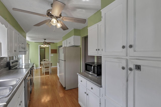 6605 Lancaster Rd SE, Hebron, OH 43025 - kitchen featuring stainless steel appliances, exhaust hood, wood finished floors, white cabinetry, and a ceiling fan