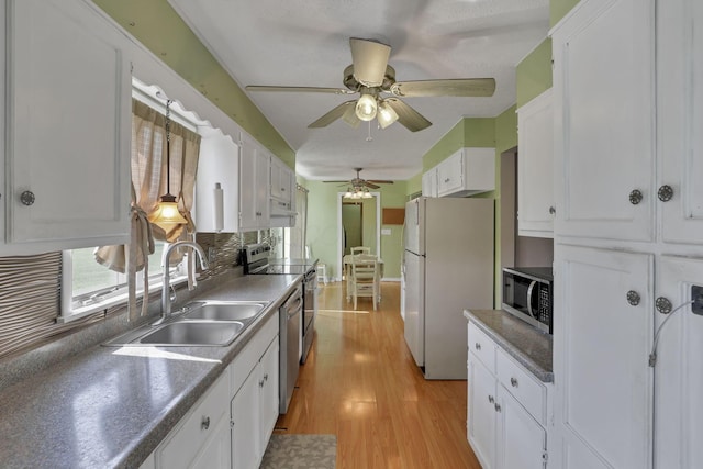 6605 Lancaster Rd SE, Hebron, OH 43025 - kitchen with appliances with stainless steel finishes, light wood finished floors, white cabinets, ceiling fan, and decorative backsplash