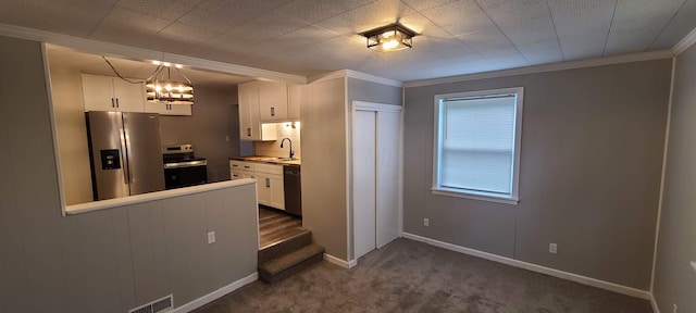 1710 Hess Blvd, Columbus, OH 43212 - kitchen with stainless steel appliances, ornamental molding, white cabinets, dark carpet, and a chandelier