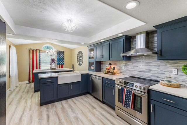 6651 Lancaster Rd, Hebron, OH 43025 - kitchen featuring wall chimney exhaust hood, appliances with stainless steel finishes, a chandelier, a peninsula, and light countertops