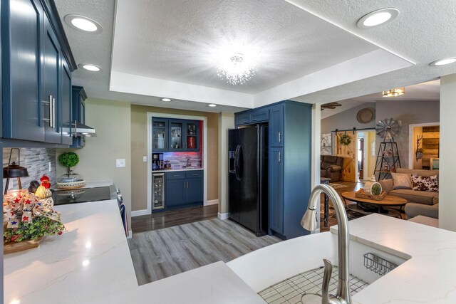 6651 Lancaster Rd, Hebron, OH 43025 - kitchen featuring black fridge, blue cabinetry, a textured ceiling, a raised ceiling, and backsplash