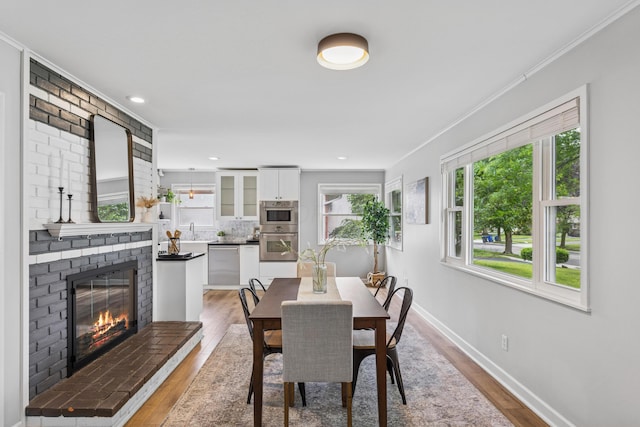 1838 Merriweather Dr, Columbus, OH 43221 - dining area with light wood-style floors, ornamental molding, a brick fireplace, and recessed lighting