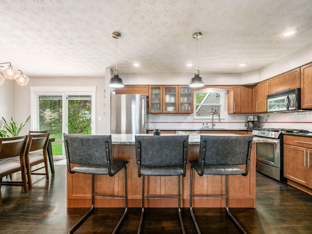5247 Heathmoor St, Columbus, OH 43235 - kitchen featuring appliances with stainless steel finishes, brown cabinetry, a textured ceiling, plenty of natural light, and recessed lighting