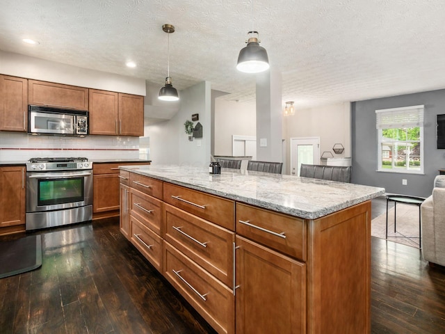 5247 Heathmoor St, Columbus, OH 43235 - kitchen featuring appliances with stainless steel finishes, dark wood-type flooring, open floor plan, brown cabinetry, and a textured ceiling
