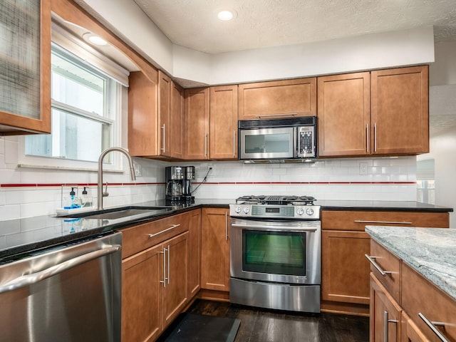 5247 Heathmoor St, Columbus, OH 43235 - kitchen with stainless steel appliances, dark wood finished floors, brown cabinets, dark stone counters, and a textured ceiling