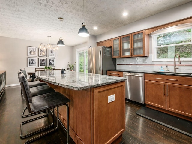 5247 Heathmoor St, Columbus, OH 43235 - kitchen with appliances with stainless steel finishes, brown cabinets, a kitchen island, dark stone counters, and a textured ceiling