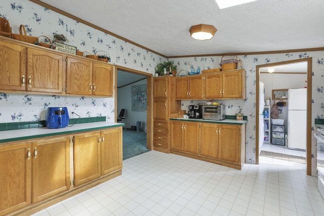 11791 Coontz Rd, Orient, OH 43146 - kitchen featuring wallpapered walls, crown molding, freestanding refrigerator, a textured ceiling, and brown cabinets