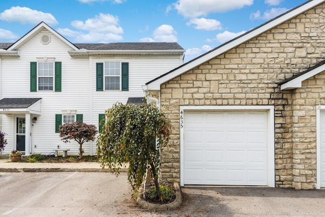 4635 Shalers Dr Unit 44D, Columbus, OH 43228 - view of side of property with stone siding, a shingled roof, and an attached garage