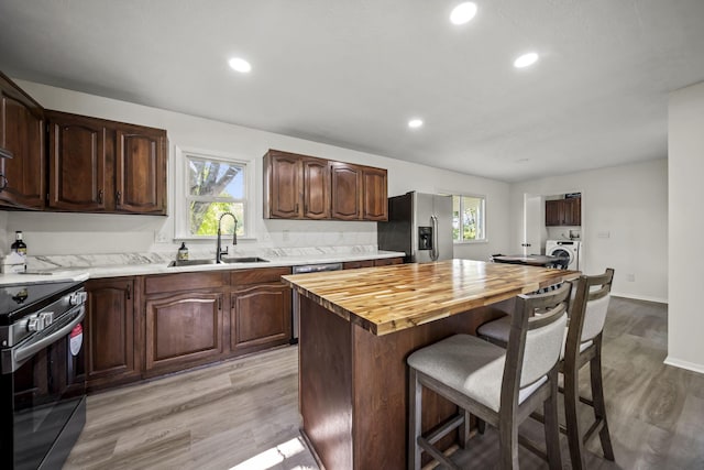 8149 Outville Rd SW, Pataskala, OH 43062 - kitchen featuring appliances with stainless steel finishes, washer / clothes dryer, a breakfast bar area, light wood-style flooring, and recessed lighting