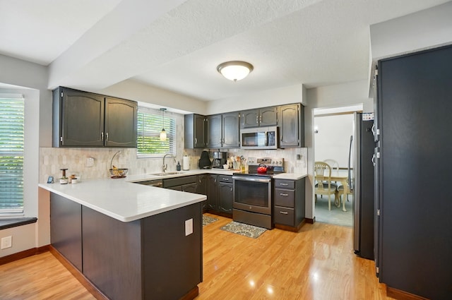 3383 Parkbrook Dr, Grove City, OH 43123 - kitchen with stainless steel appliances, a peninsula, decorative backsplash, and light wood-style flooring