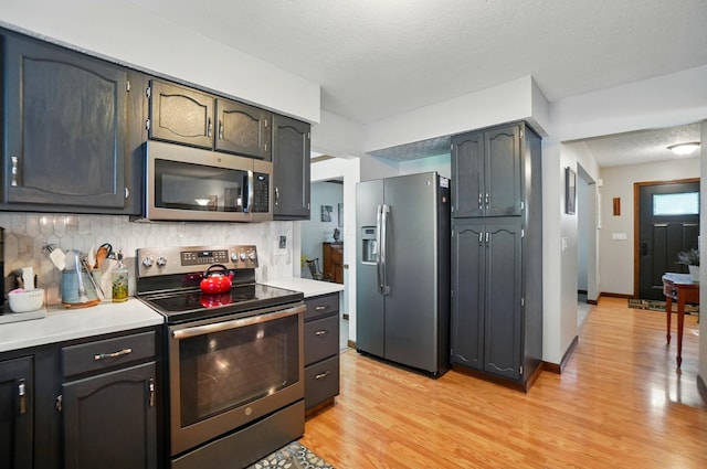 3383 Parkbrook Dr, Grove City, OH 43123 - kitchen featuring appliances with stainless steel finishes, decorative backsplash, light wood-style floors, light countertops, and a textured ceiling