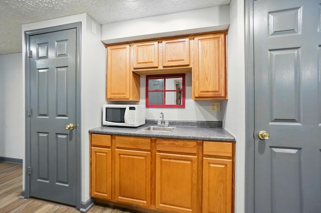 3383 Parkbrook Dr, Grove City, OH 43123 - kitchen with white microwave, dark countertops, a textured ceiling, and light wood finished floors