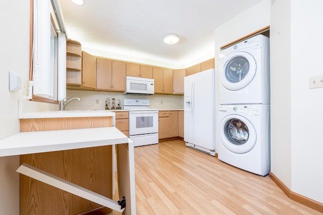 129 Chase Ave Unit 102L, Russells Point, OH 43348 - kitchen featuring white appliances, stacked washing machine and dryer, light countertops, light wood-type flooring, and a peninsula