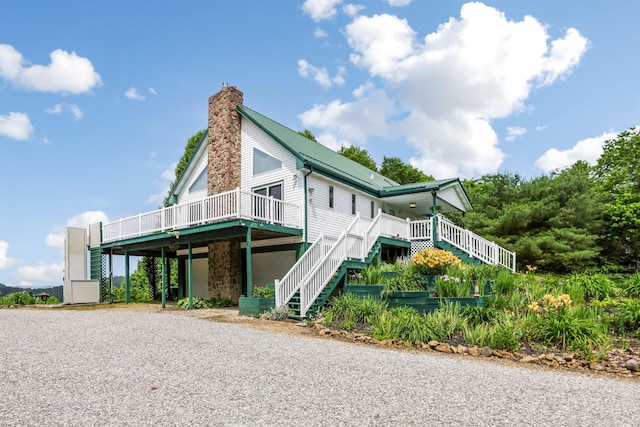 51801 State Route 671, Londonderry, OH 45647 - view of side of property featuring stairs, a chimney, gravel driveway, stone siding, and a metal roof