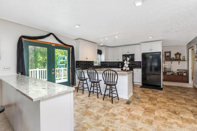 51801 State Route 671, Londonderry, OH 45647 - kitchen featuring black appliances, a peninsula, white cabinets, tasteful backsplash, and a breakfast bar