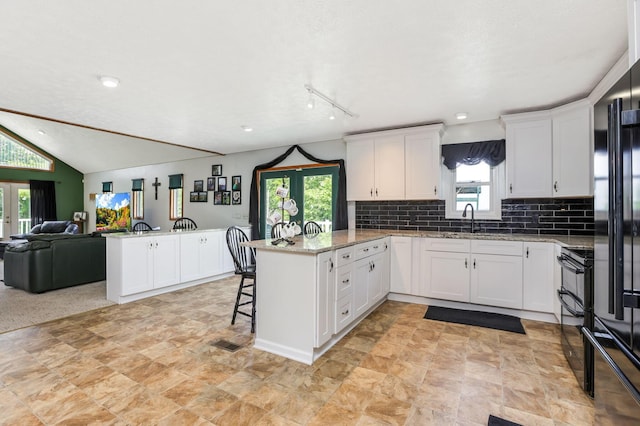51801 State Route 671, Londonderry, OH 45647 - kitchen with a peninsula, open floor plan, white cabinetry, tasteful backsplash, and a kitchen bar