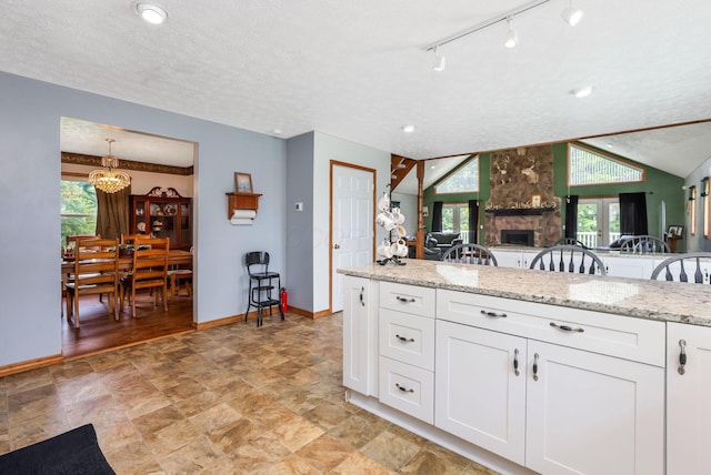 51801 State Route 671, Londonderry, OH 45647 - kitchen with a chandelier, white cabinetry, light stone countertops, a fireplace, and stone finish flooring