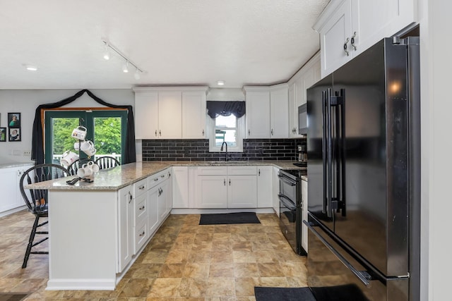 51801 State Route 671, Londonderry, OH 45647 - kitchen with black appliances, a peninsula, white cabinets, a kitchen bar, and light stone countertops