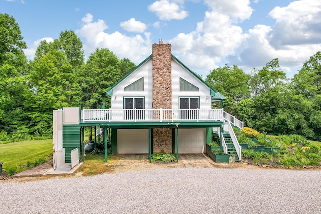 51801 State Route 671, Londonderry, OH 45647 - view of front of home with stairway, a deck, gravel driveway, a chimney, and an attached garage
