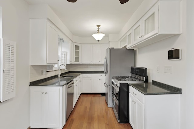 3505 Dresden St, Columbus, OH 43224 - kitchen featuring stainless steel appliances, dark countertops, white cabinets, glass insert cabinets, and wood finished floors