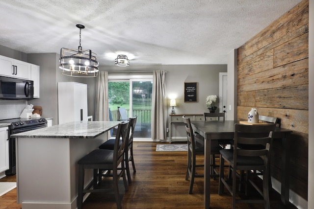 4634 State Route 61, Sunbury, OH 43074 - kitchen with black appliances, a center island, light stone counters, a breakfast bar area, and dark wood finished floors