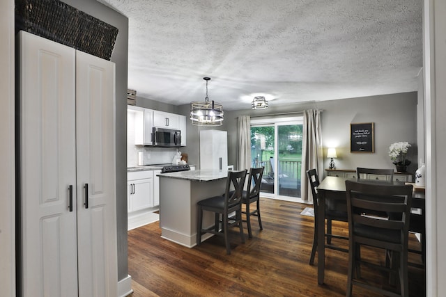 4634 State Route 61, Sunbury, OH 43074 - kitchen with stainless steel microwave, a kitchen island, a chandelier, dark wood-type flooring, and a breakfast bar area