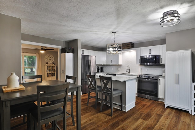 4634 State Route 61, Sunbury, OH 43074 - kitchen with stainless steel appliances, a kitchen island, decorative backsplash, white cabinetry, and dark wood-style floors