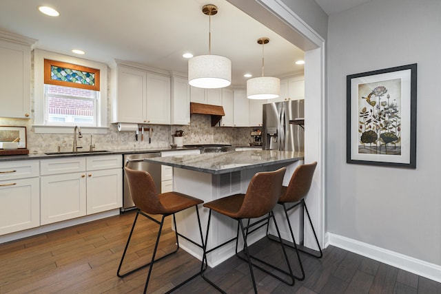 678 S Cassingham Rd, Columbus, OH 43209 - kitchen with appliances with stainless steel finishes, a breakfast bar, dark wood-style floors, backsplash, and white cabinetry