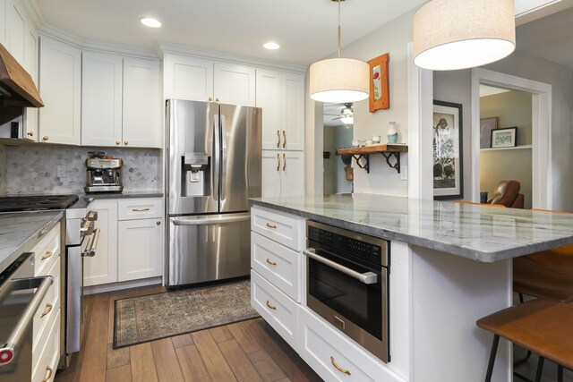 678 S Cassingham Rd, Columbus, OH 43209 - kitchen featuring appliances with stainless steel finishes, a kitchen bar, dark wood-style flooring, white cabinetry, and recessed lighting