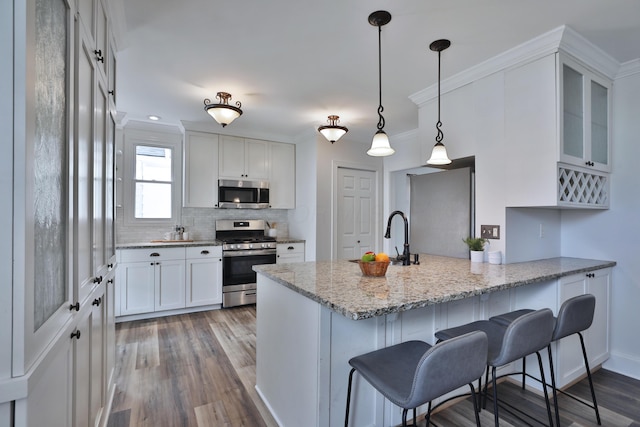 274 E Jenkins Ave, Columbus, OH 43207 - kitchen with stainless steel appliances, a peninsula, a kitchen breakfast bar, wood finished floors, and white cabinetry