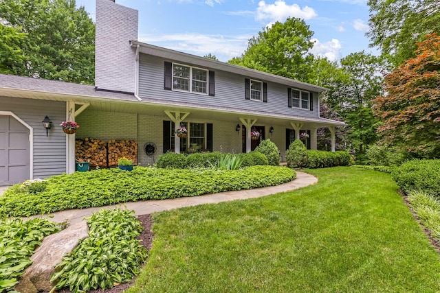 2211 Welsh Hills Rd NE, Granville, OH 43023 - view of front of house with a chimney, a front lawn, an attached garage, brick siding, and a porch