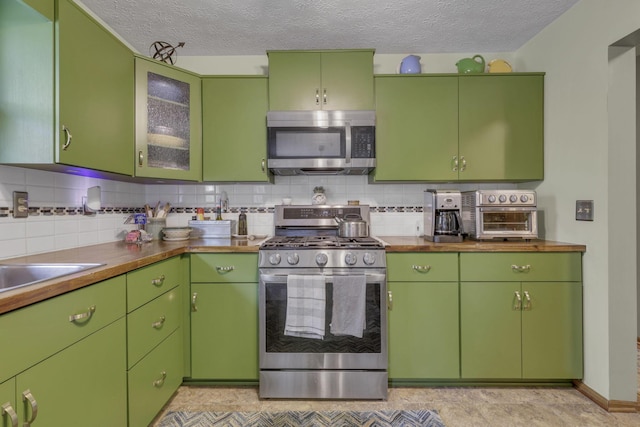 1588 Constitution Dr, Newark, OH 43055 - kitchen with stainless steel appliances, a textured ceiling, backsplash, and glass insert cabinets