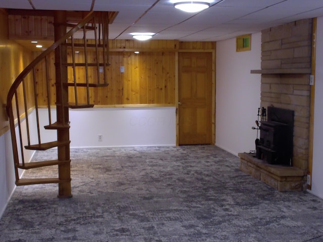 1110 Burr Oak Blvd, Nelsonville, OH 45764 - unfurnished living room with carpet flooring, stairs, a wood stove, wood walls, and a drop ceiling
