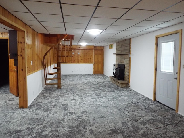1110 Burr Oak Blvd, Nelsonville, OH 45764 - unfurnished living room featuring carpet, a wood stove, stairs, wood walls, and a drop ceiling