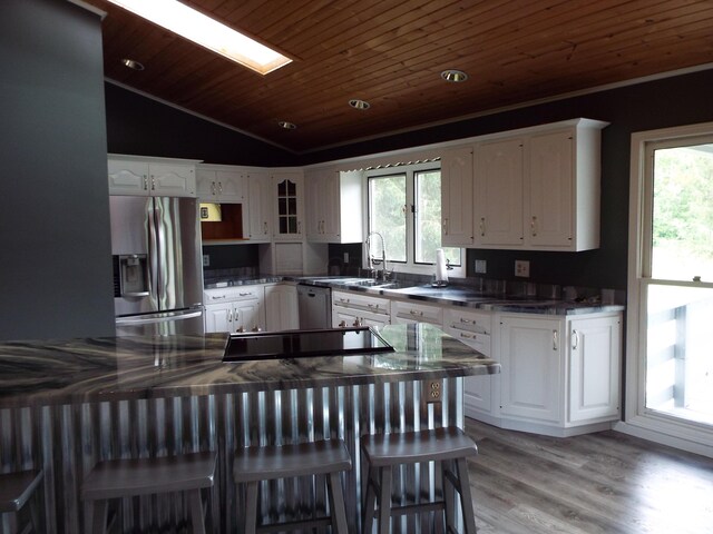 1110 Burr Oak Blvd, Nelsonville, OH 45764 - kitchen featuring stainless steel fridge, vaulted ceiling, dark countertops, healthy amount of natural light, and white cabinets
