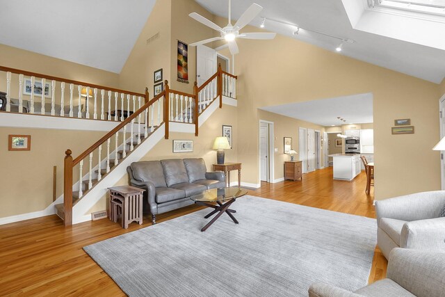 7661 Norhill Rd, Columbus, OH 43235 - living area with light wood-style flooring, high vaulted ceiling, track lighting, ceiling fan, and stairway
