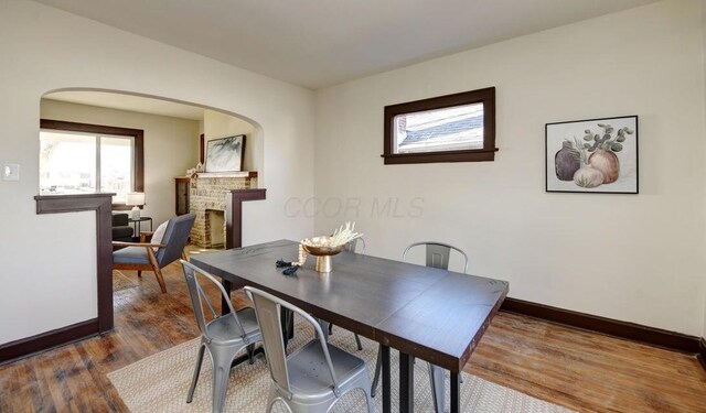 798 E Mithoff St, Columbus, OH 43206 - dining room with wood finished floors, arched walkways, and a fireplace