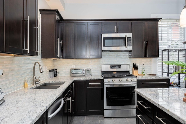 1066 City Park Ave, Columbus, OH 43206 - kitchen featuring appliances with stainless steel finishes, tile patterned floors, light stone countertops, decorative backsplash, and dark brown cabinetry