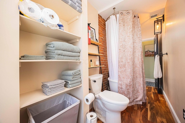 1066 City Park Ave, Columbus, OH 43206 - full bathroom featuring wood finished floors, a shower with shower curtain, and brick wall