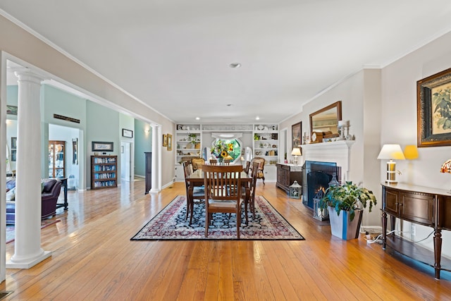 170 Joy Ln, Granville, OH 43023 - dining space featuring decorative columns, ornamental molding, built in features, light wood-style floors, and a warm lit fireplace