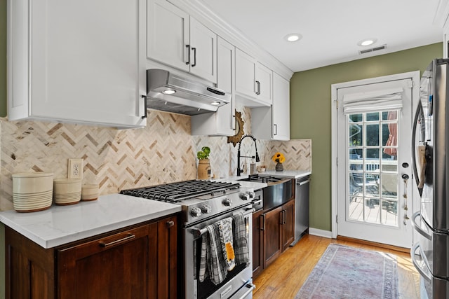 170 Joy Ln, Granville, OH 43023 - kitchen with stainless steel appliances, under cabinet range hood, white cabinets, tasteful backsplash, and light wood-type flooring